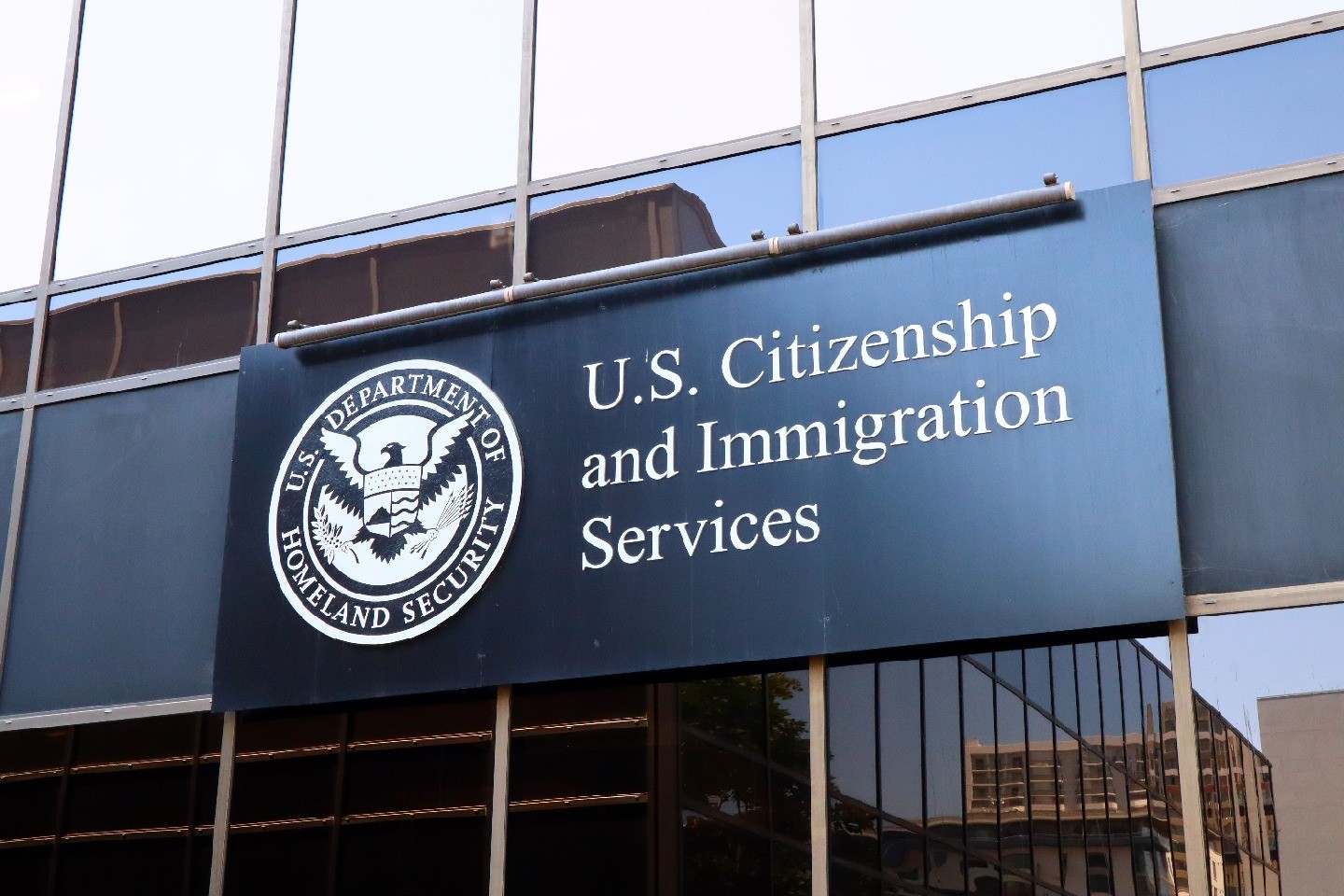 An official sign at a U.S. federal building has a Department of Homeland Security seal and reads “U.S. Citizenship and Immigration Services.”