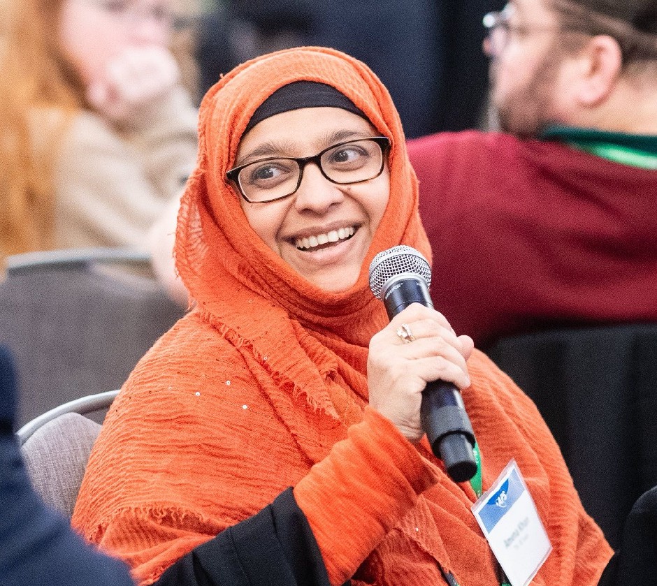 A woman wearing an orange hijab speaking into a microphone