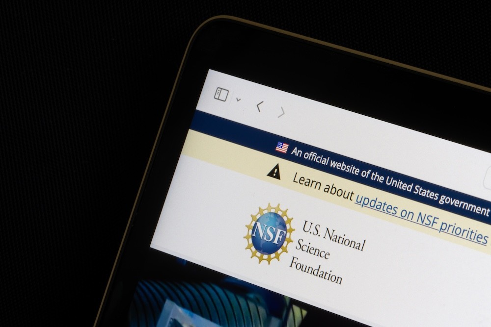 The corner of a laptop screen shows the NSF website and logo.