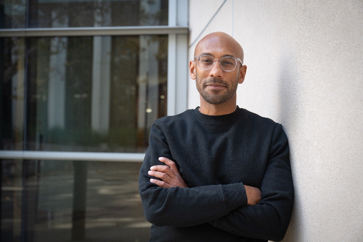 Sujit Datta, leans against a wall, with arms crossed.