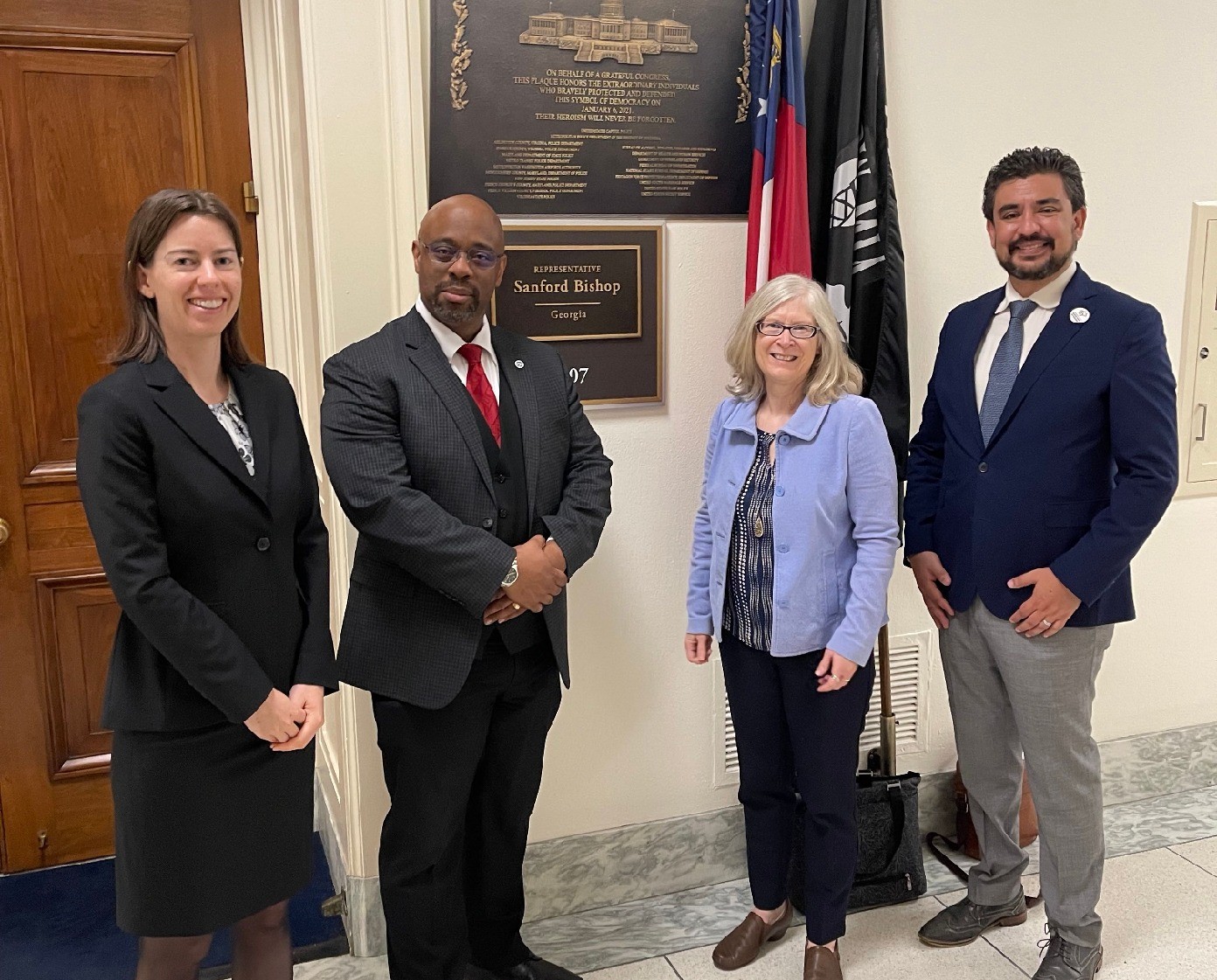 Four people pose in front of a sign marking the office of Rep. Sanford Bishop.