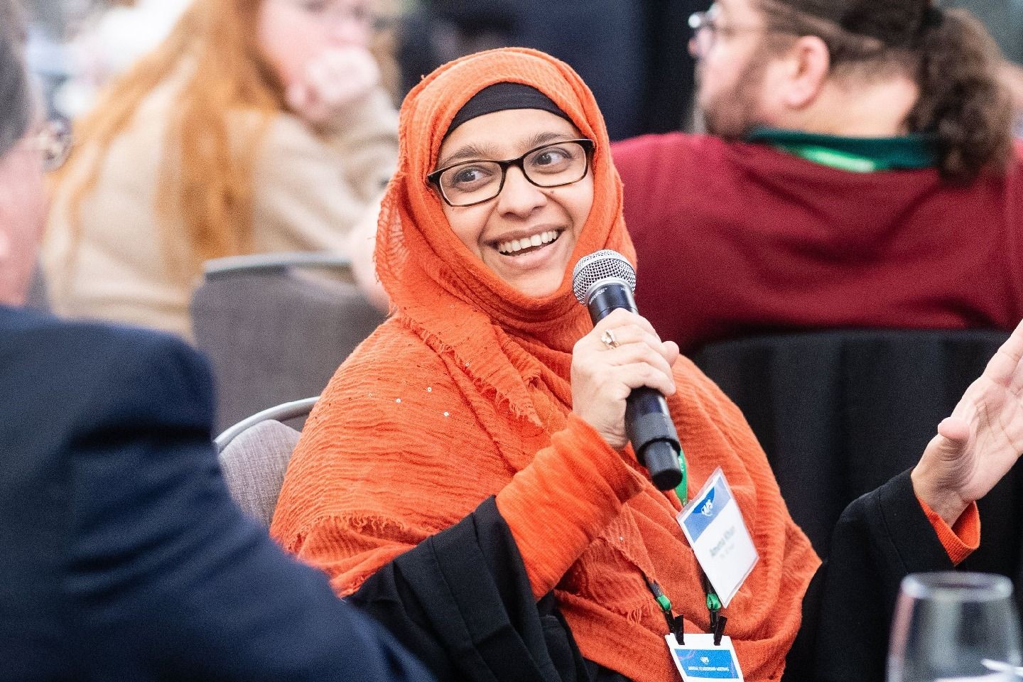 A woman wearing a hijabi speaking into a microphone