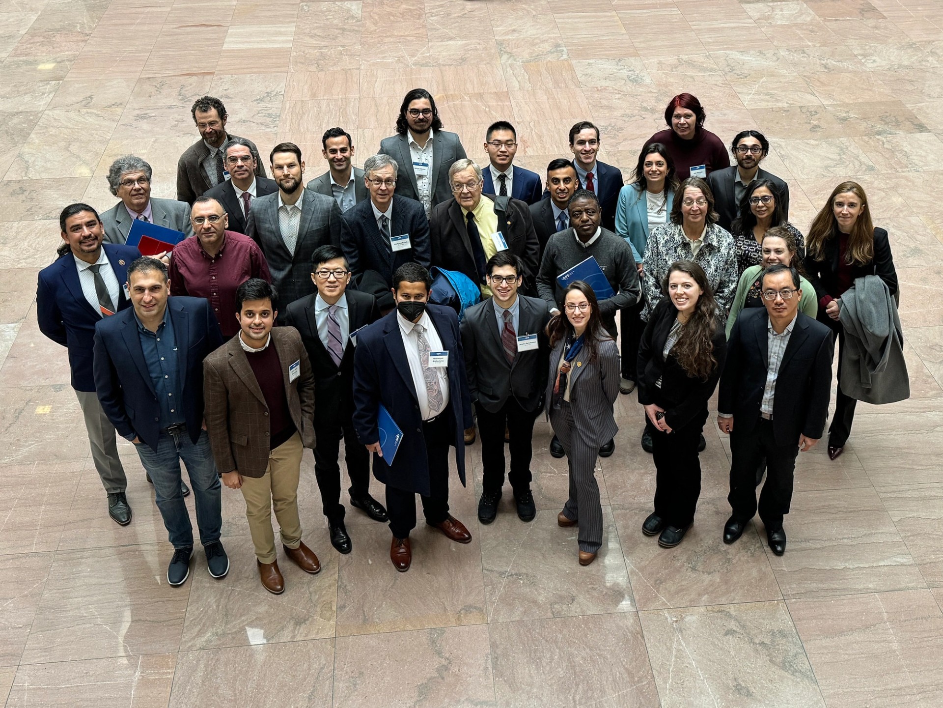 A crowd of people wearing formal clothes looks up at the camera.