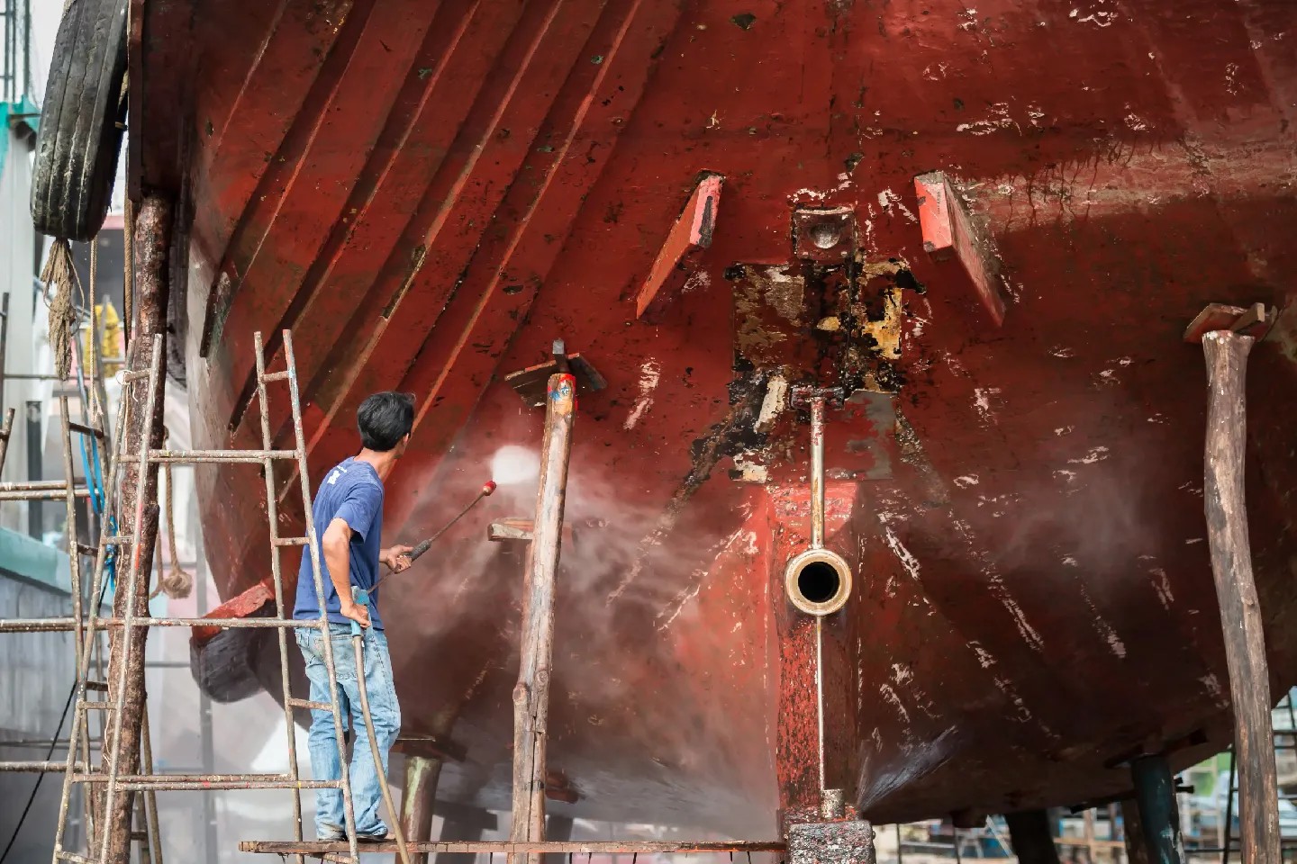 Barnacles are a problem for the shipping industry and maritime institutions. Here, a man pressure-washes a boat hull, where barnacles tend to gather.