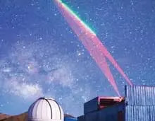 A colorful beam projected into a blue starry sky.