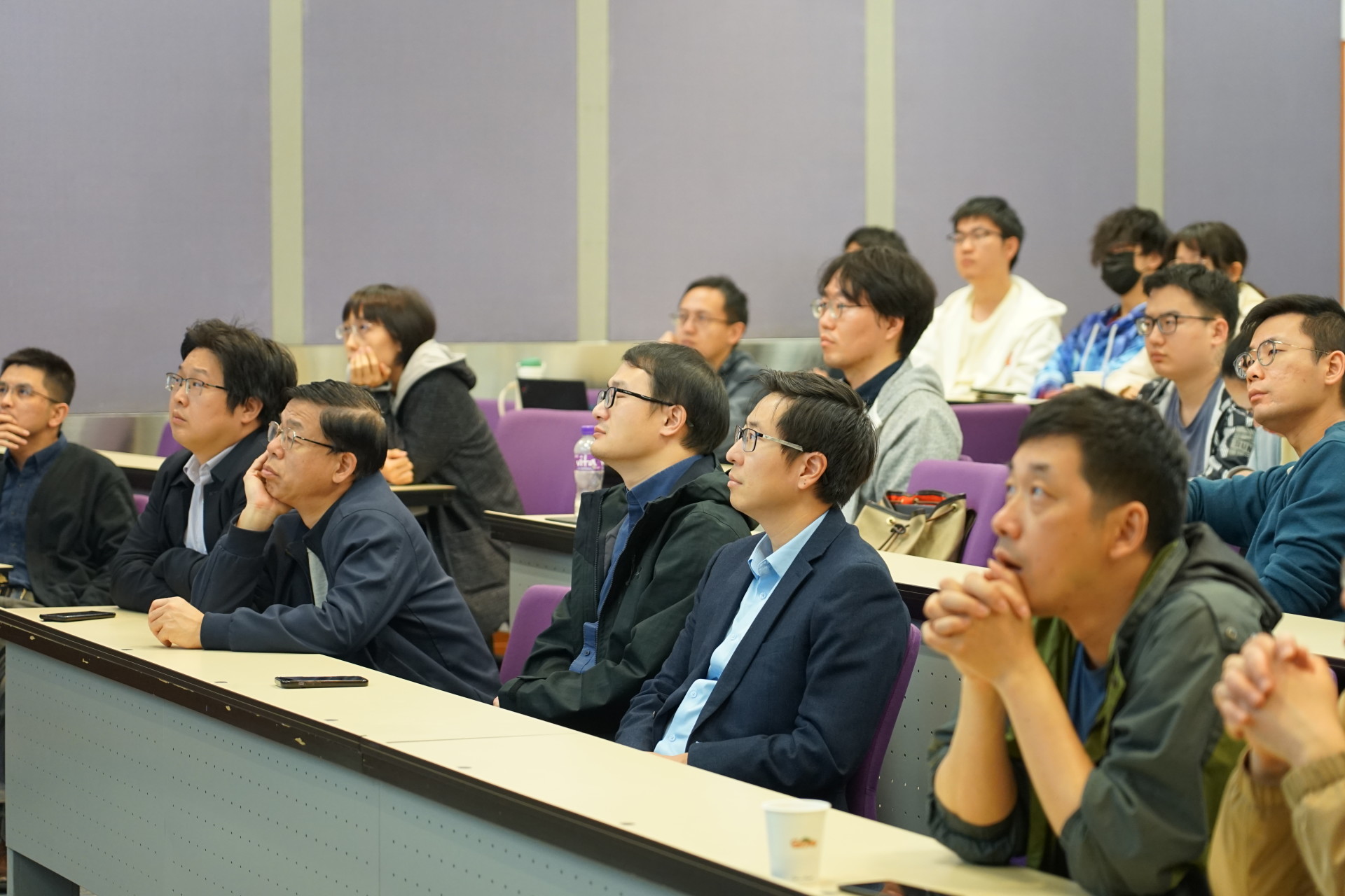 People look at a presentation on the screen in a lecture hall