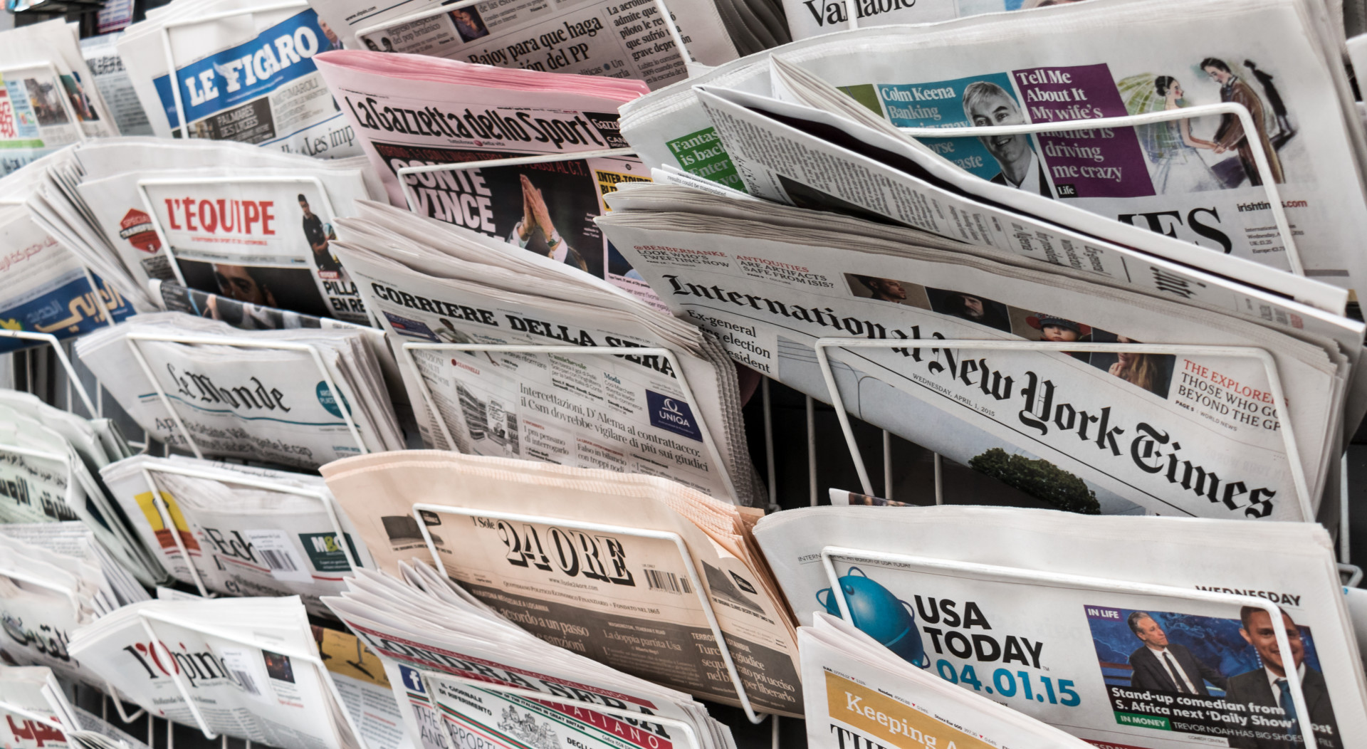 A newspaper rack holds several international newspapers