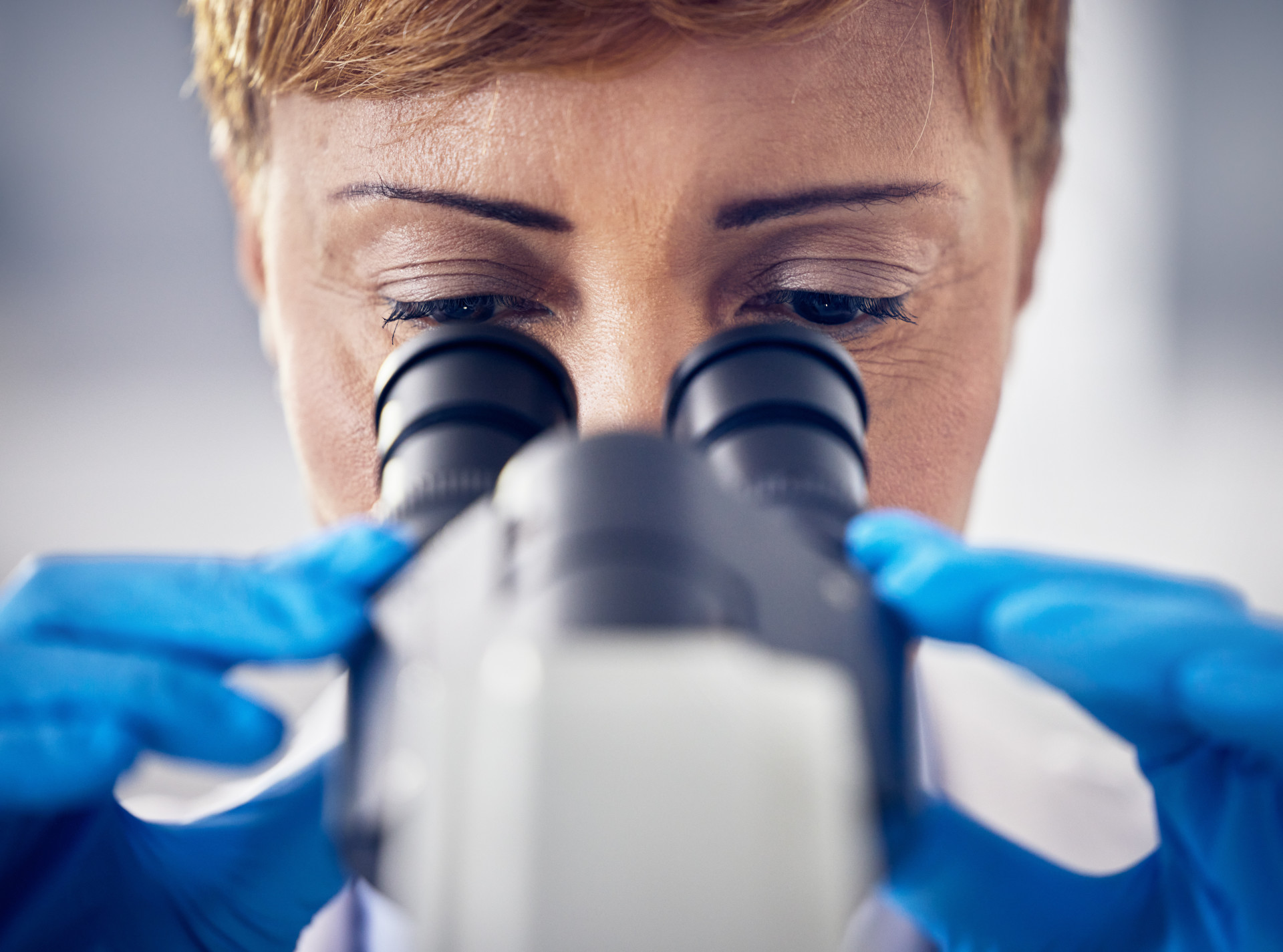 Photo of a woman looking through a microscope. 