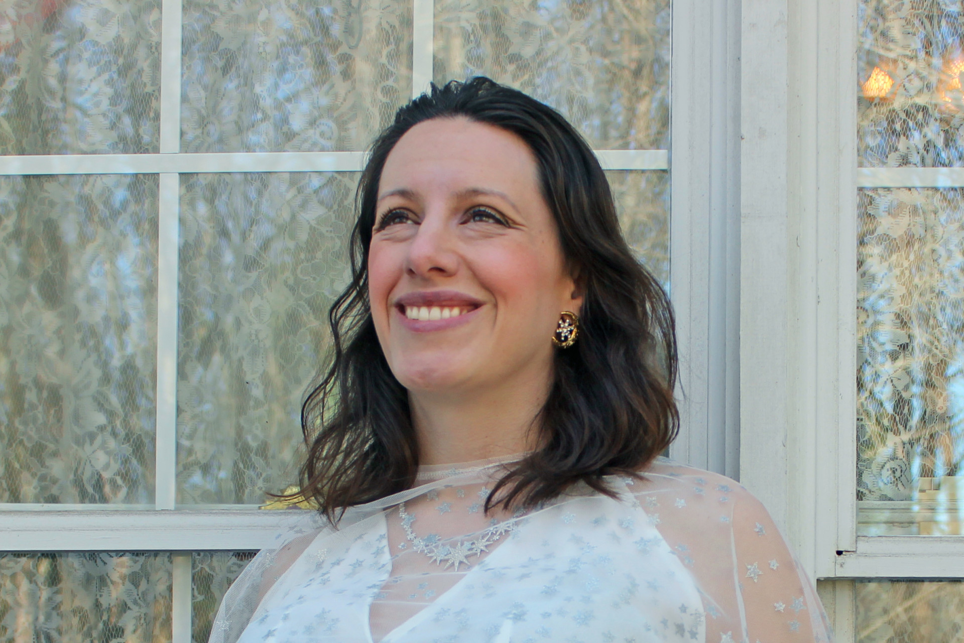 A headshot of Laura Forczyk, who is smiling and looking into the distance with windows visible behind her.