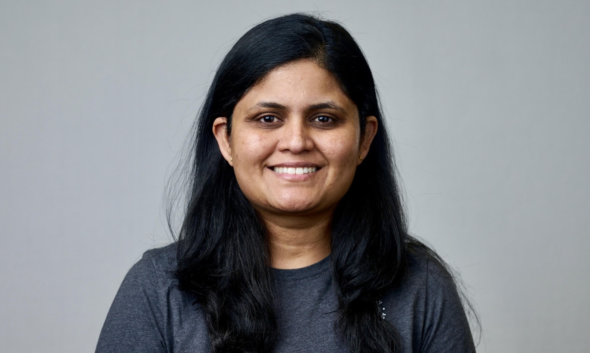 A headshot of Neha Pachauri, smiling in front of a gray background.