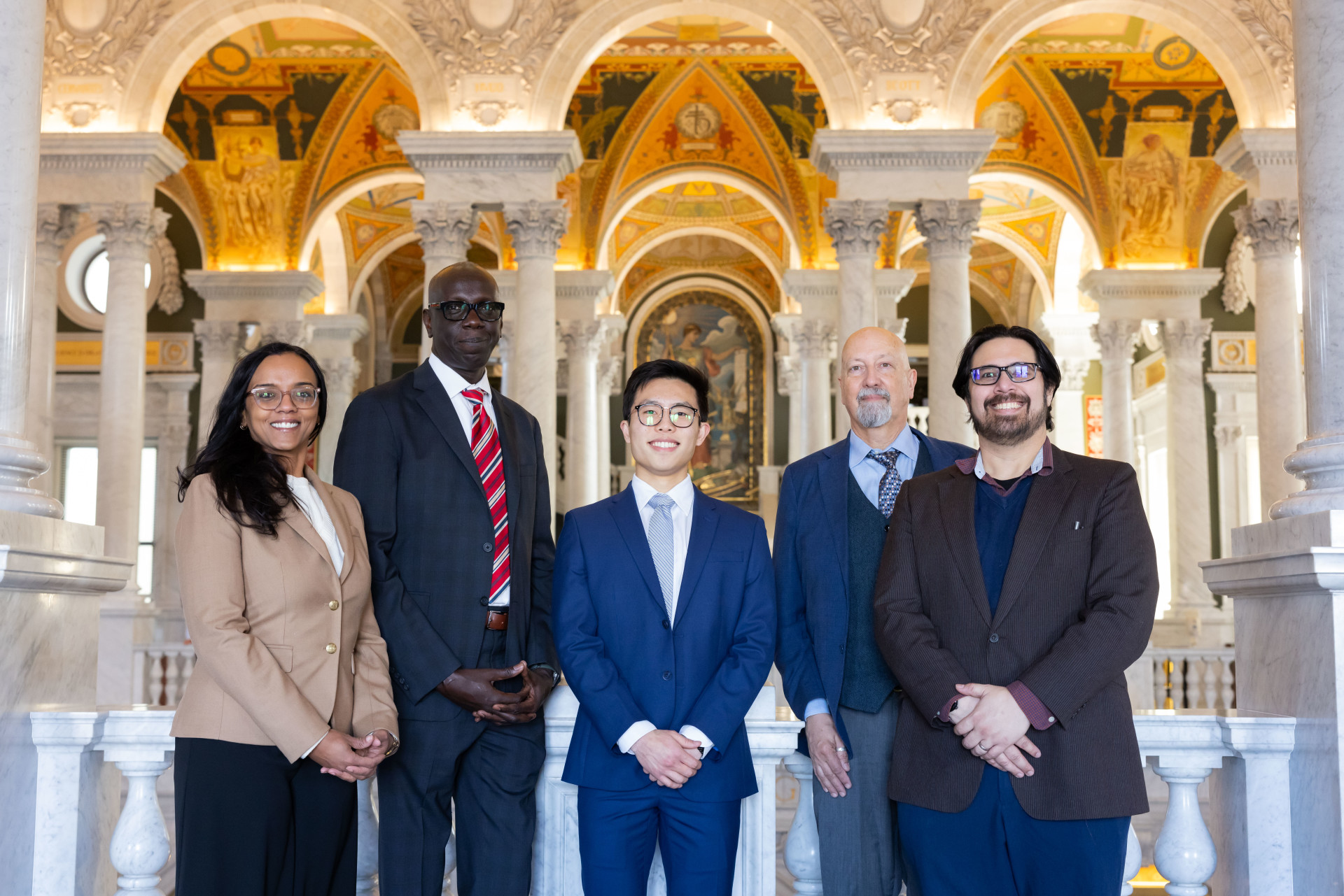Five APS members pose for a photo on Capitol Hill, with dramatic architecture visible behind them.