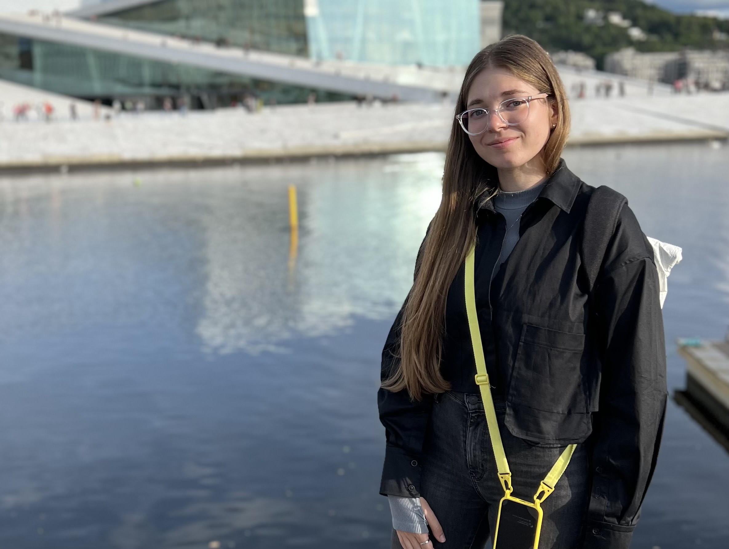 Polina Kofman stands in front of a calm waterway.
